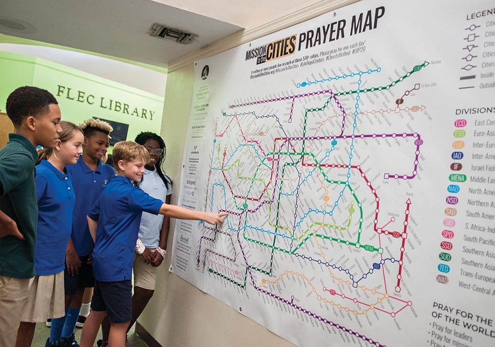 A student at Forest Lake Education Center points out the city his class is currently praying for on the Mission to the Cities map. Students and their families are praying for each of those large cities around the world so they can be opened to God’s message of hope. [Photo: Adventist Mission] 