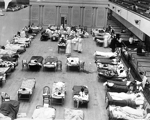 Volunteer nurses from the American Red Cross tending influenza sufferers in the Oakland Auditorium, Oakland, California, during the influenza pandemic of 1918. PC: Edward A. “Doc” Rogers0