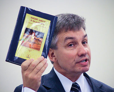 <strong>CHAPEL SPEAKER:</strong> Mikhail Kulakov, Jr., holds up a newly printed Russian Bible while speaking for a Pacific Press employee chapel service.