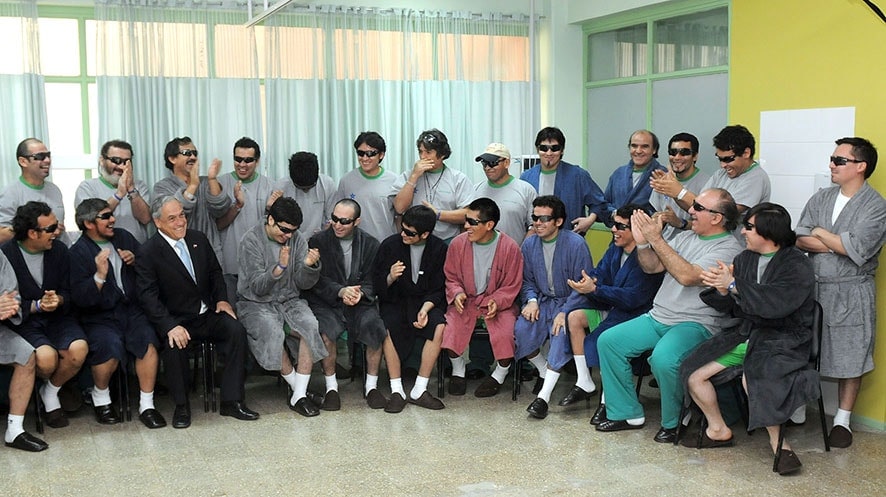 The miners celebrate in the hospital after having been rescued. They are wearing sunglasses to protect their eyes after being down in the mine for 69 days. [Chilean Government]