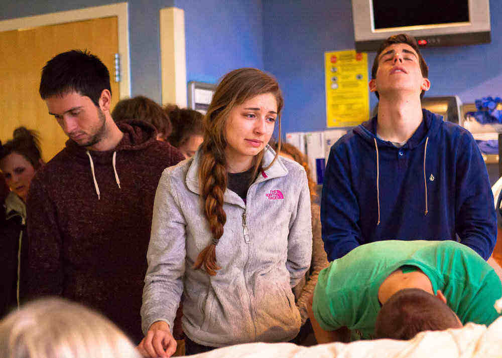 Madison’s friends from Walla Walla University gathering to pray and sing around her hospital bed on Feb. 11, 2015. From left, Eli Wart, Mindy Robinson, Matthew Cosaert (standing), and Urijah Saenz. (Natalie St. John / Chinook Observer)