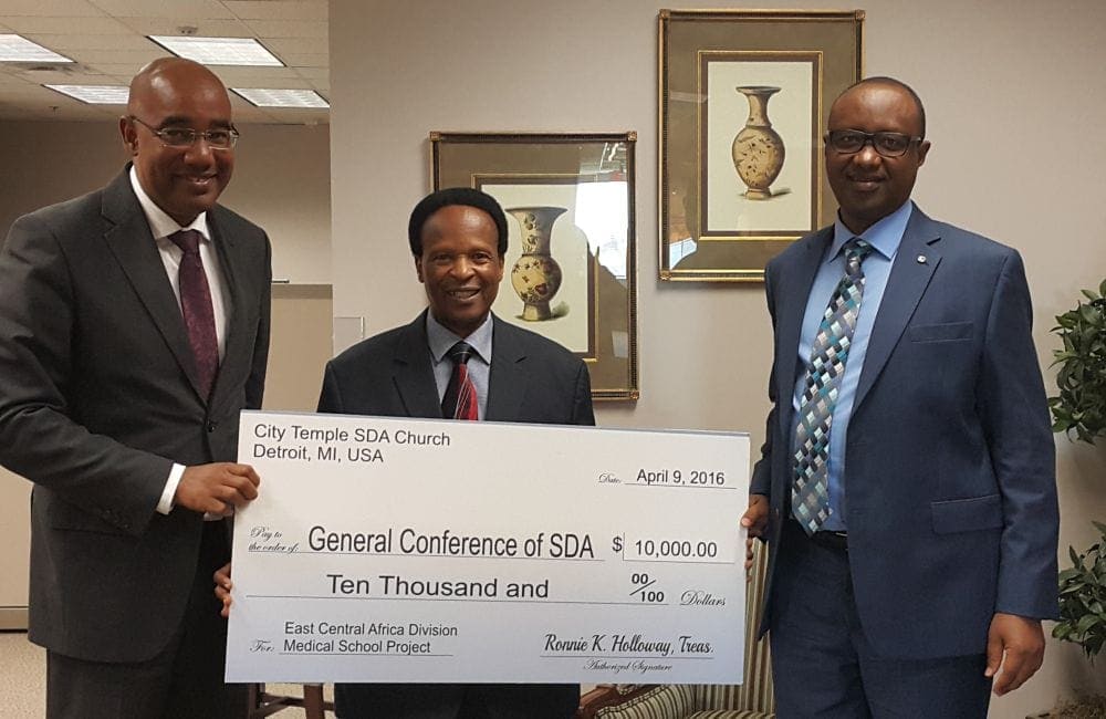 The three top leaders of the East-Central Africa Division — Alain Coralie, left, executive secretary; Blasious Ruguri, center, president; Jerome Habimana, treasurer — posing with the check. (Courtesy of Detroit City Temple)