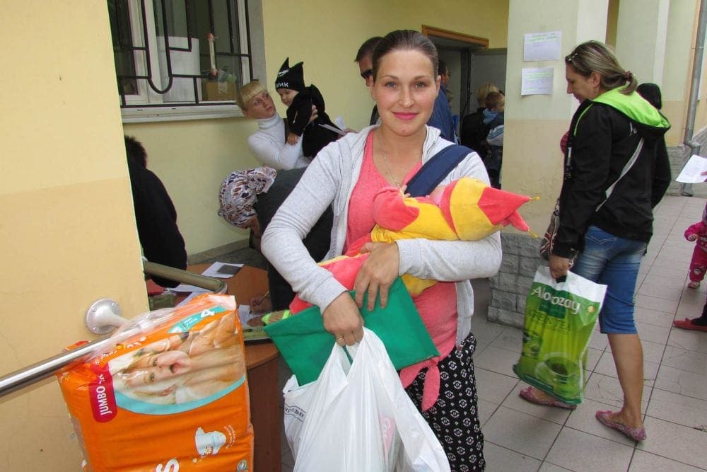 A mother picking up a personal hygienic kit with baby items at an ADRA distribution center.