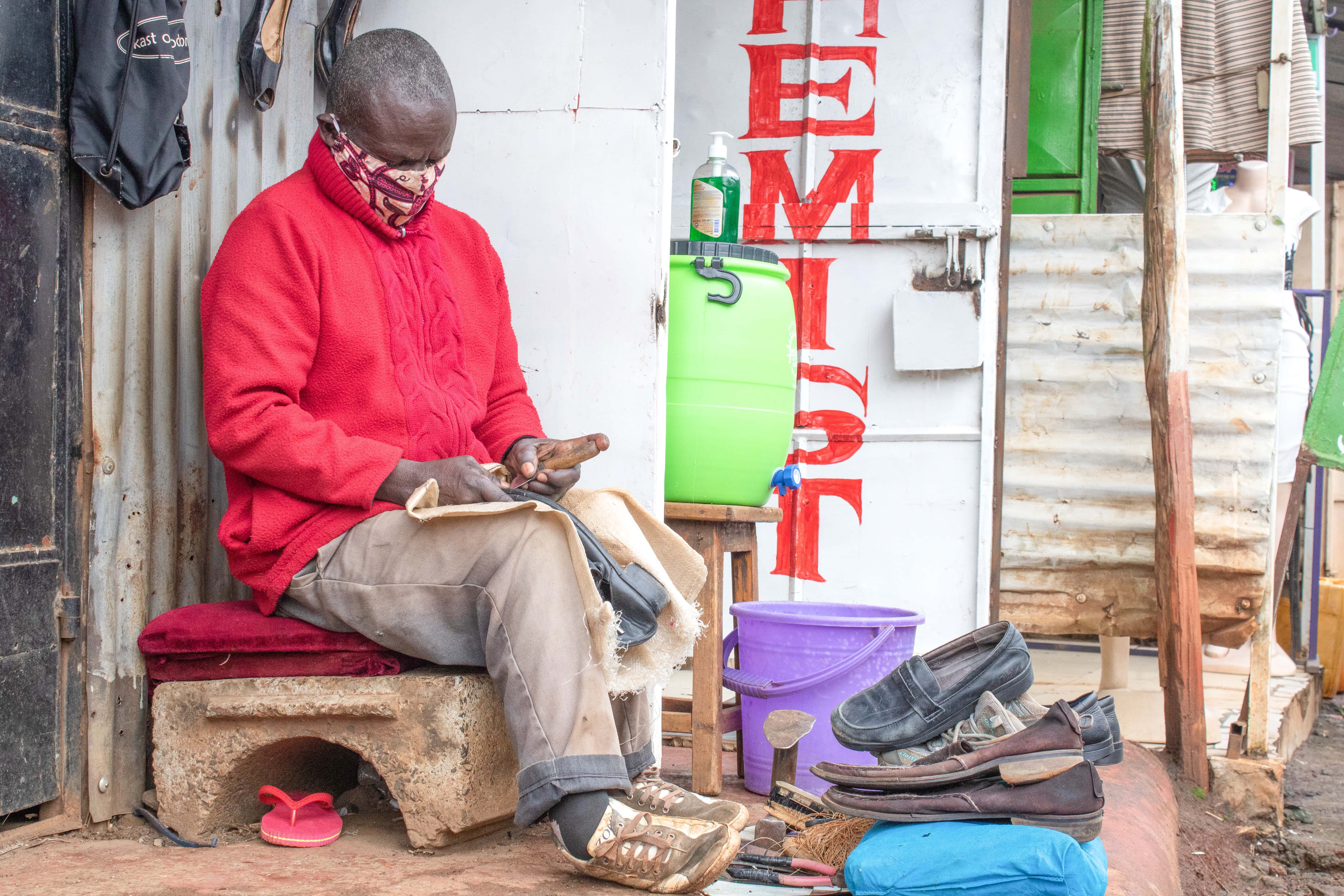 Samuel Onang’o, a cobbler with a disability, is hard at work on several pairs of shoes. [Photo: ADRA Kenya]