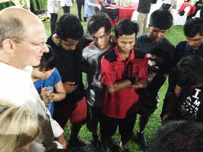 World church President Ted N.C. Wilson, left, praying with 13 One Year in Mission volunteers, who were among the 100 people who trained at the evangelism center. Photo: SSD