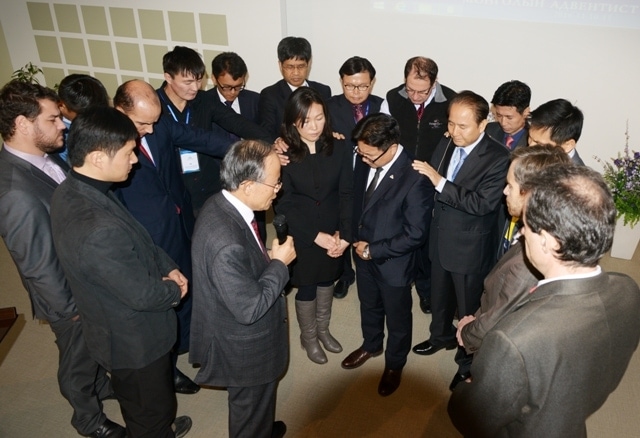 Northern Asia-Pacific Division president Pastor Jairyong Lee, center, prays with staff for a missionary. (NSD photo)