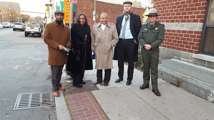 Charles and Miriam Battles (left), with former PFA principal Auldwin Humphrey, stand on the exact bus stop spot where the attack occurred. They were joined by a representative from the city of Boston and a park guide.