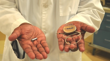 A physician holds the holds the Micra® Transcatheter Pacing System, left, and compares it to the traditional pacemakers, right, which require cardiac wires (also known as leads) and a bulky surgical “pocket” under the skin. Florida Hospital Memorial Medical Center and Florida Hospital New Smyrna recently began offering the world’s smallest pacemaker. [Photo: Florida Hospital News]