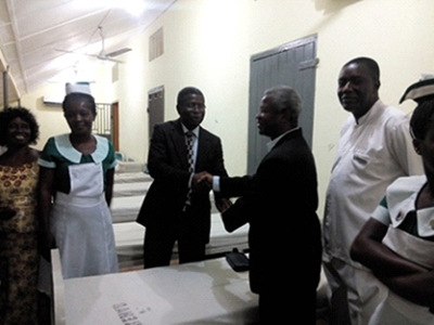 Pastor Samuel Adama Larmie, President of Southern Ghana Union Conference, hands over keys to Dr. Akwesi Osei. Hospital administrators and church leaders in front of the ward