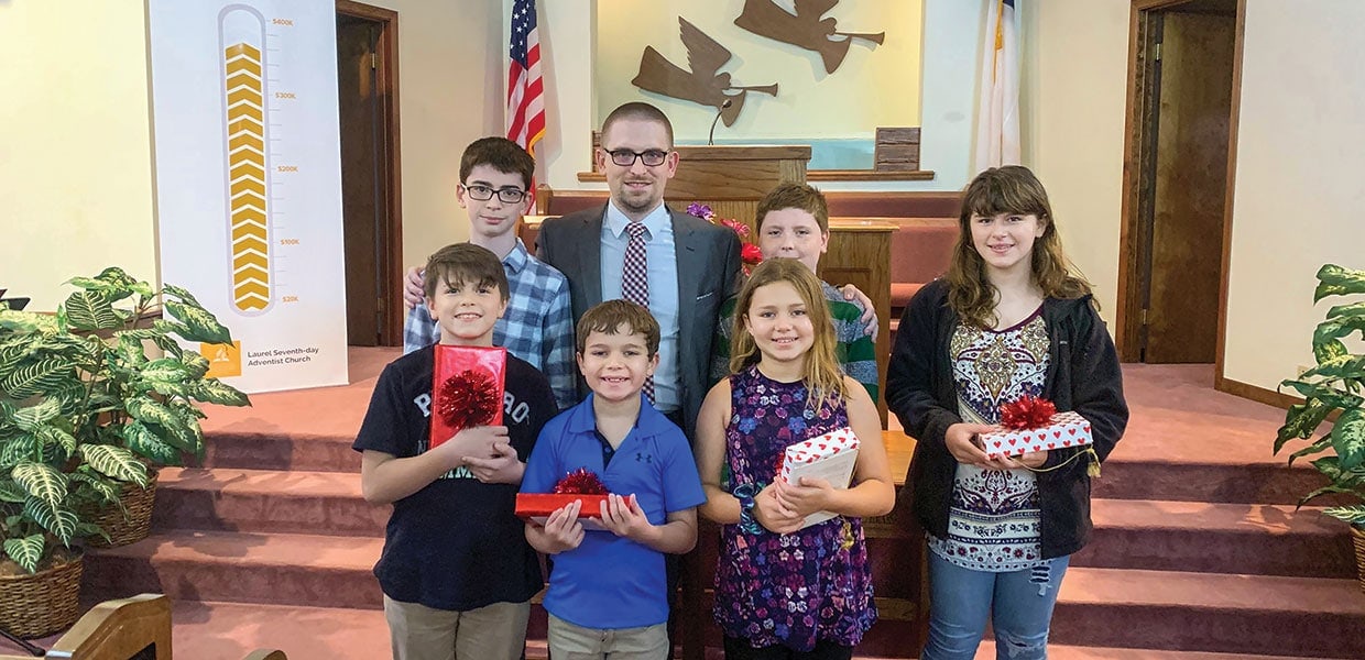 Jim Stewart (second row, second from left), pastor of the Laurel Adventist church, puts his arms around his sons and poses with members of two of the local church families after their baptism. [Photo: Gulf States Conference]