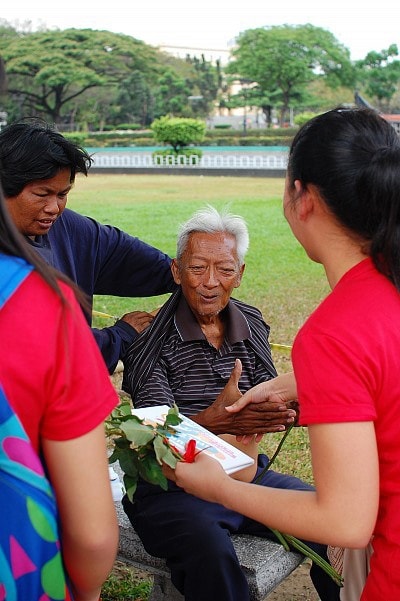 82-year-old Mang Noel reacts upon receiving a flower and encouragement cards from a group of Adventist youth celebrating Global Youth Day through acts of compassion in a Manila park, March 15. [Photo: RJ Almocera]
