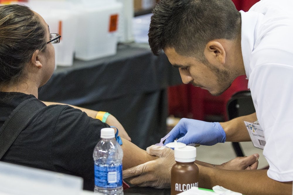 David Hernandez. a senior nursing major from Southwestern Adventist University, tending to a patient. More than 70 students and faculty from the Keene, Texas-based university are volunteering at the three-day event in San Antonio. Photo: SWAU