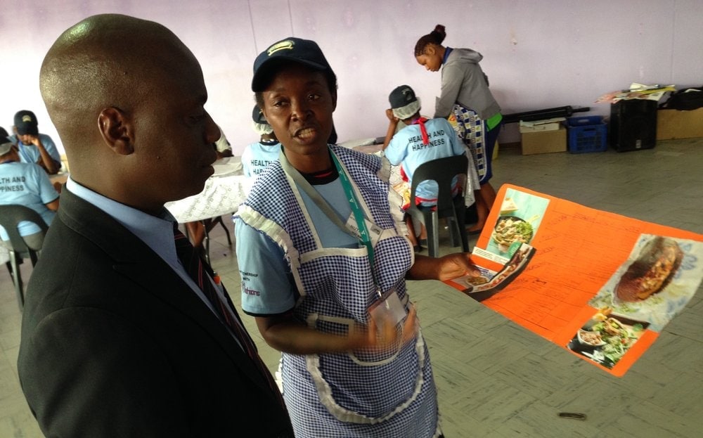 A nutrition center volunteer showing a meal plan developed by a patient to Innocent Gwizo, director of health ministries for the Zimbabwe Union Conference, at the free clinic on Thursday, May 28. (Andrew McChesney / AR)