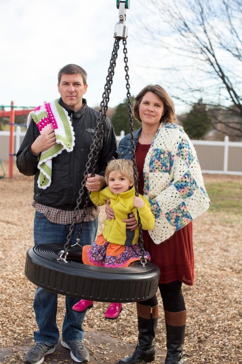 Summer Porter and husband David Burke pose with their daughter and crocheted baby blankets. Photo by Associated Press/Allison Shelley for Visitor Magazine