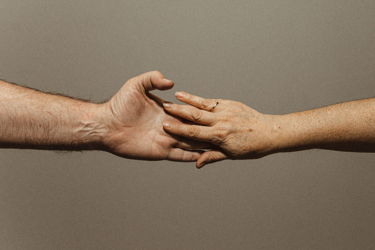 A photo of two hands gently reaching toward each other, capturing a moment of connection and support.